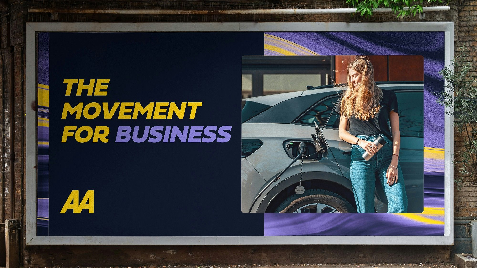 Image shows the AA's new branding on a landscape billboard headlined 'the movement for business' in yellow and purple font, next to a photo of a person leaning on a car while it is being refuelled