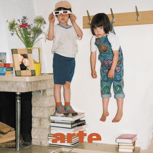 Image from Arte's Brothers and Sisters campaign, showing a photo of a child wearing sunglasses standing on a tower of books with another child with a fringe and dungarees hanging from a coat hook