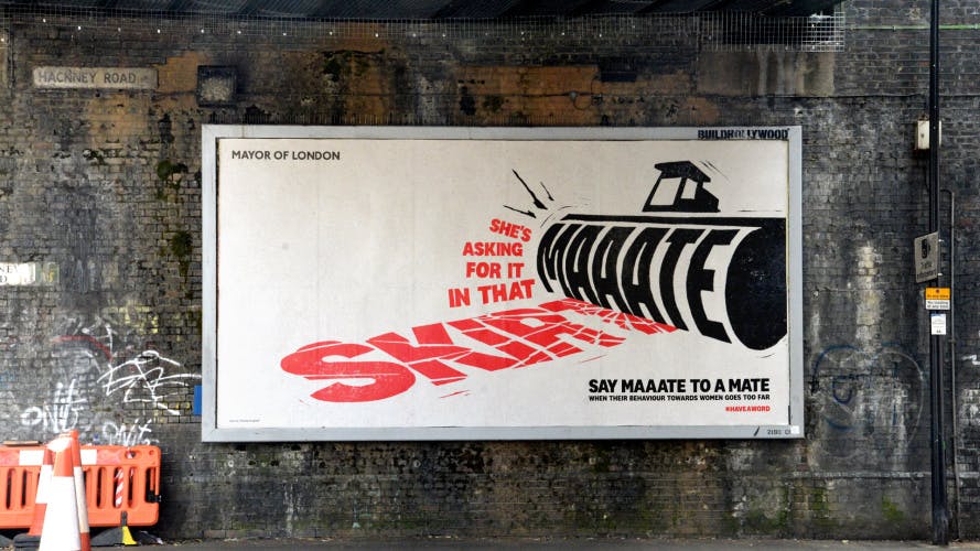 Photograph of the Mayor of London campaign Maaate, which shows the words 'She's asking for it in that skirt' being rolled out by a steam roller emblazoned with the word 'Maaate'