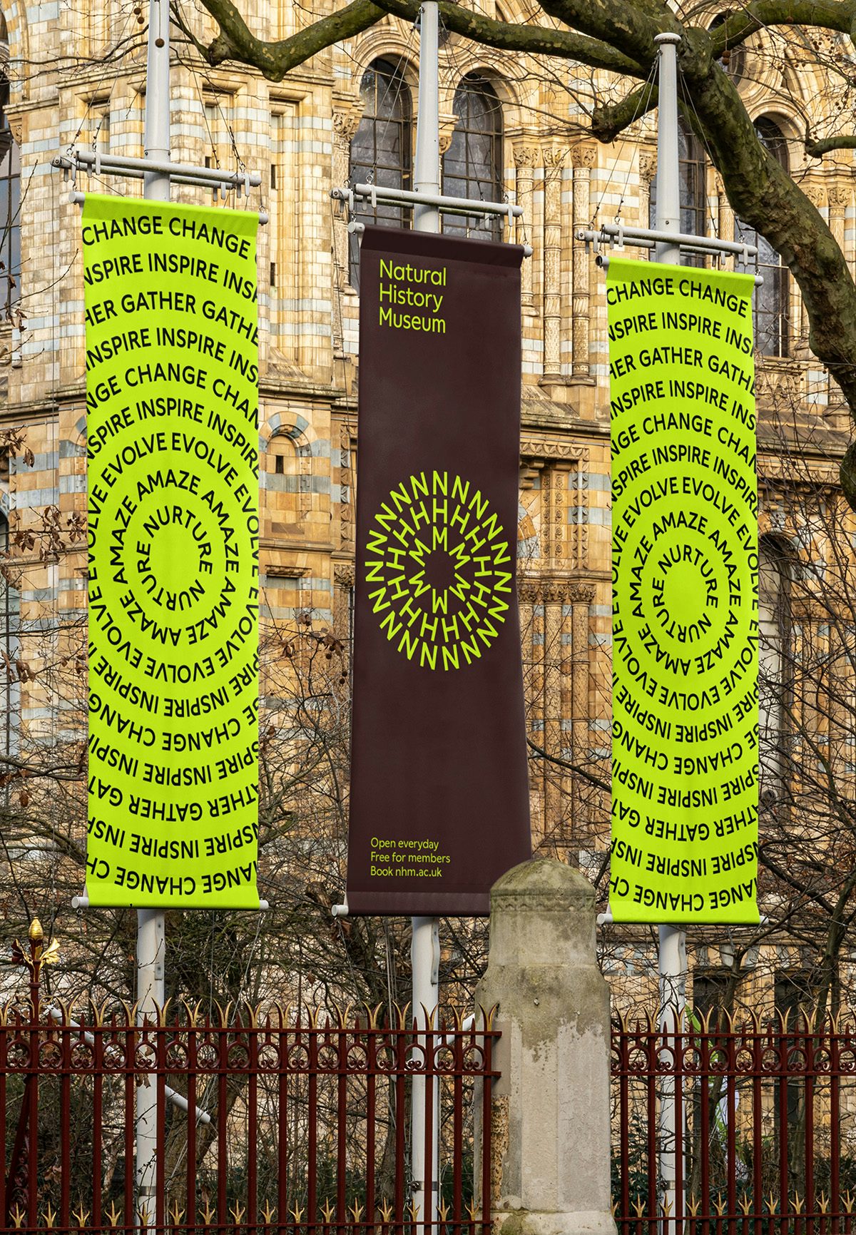 Image shows the new Natural History Museum branding on vertical outdoor banners, showing the initials 'NHM' arranged in concentric circles on a neon yellow background, and one with the letters in neon yellow on a dark grey background