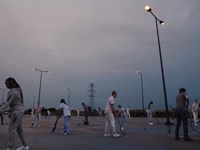 Still from the music video for Schwer by Paul Kalkbrenner showing visualisations of people walking around a car park at dusk appearing to hold metal detectors