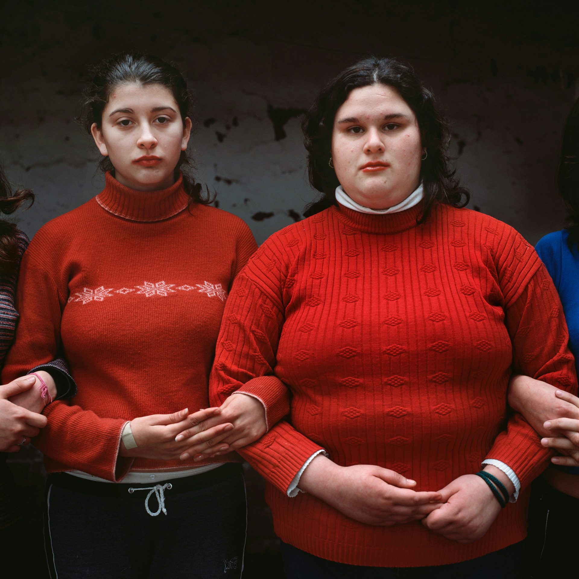 Photograph by Alessandra Sanguinetti of two girls with a slightly sombre expression wearing red jumpers and facing the camera