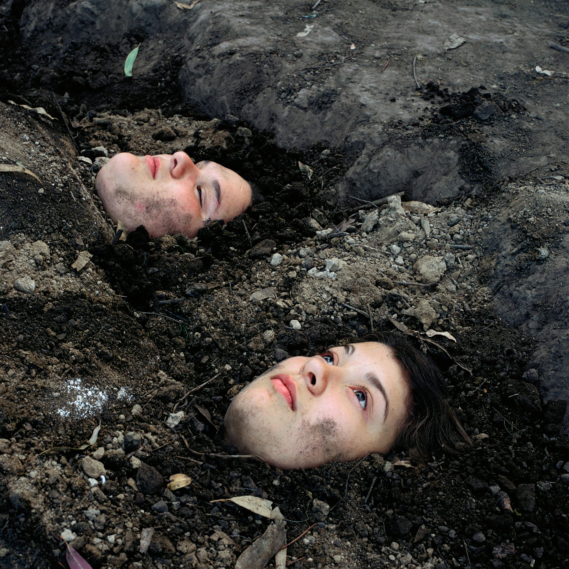 Photograph by Alessandra Sanguinetti of two girls buried in dirt with only their heads showing as they look above them