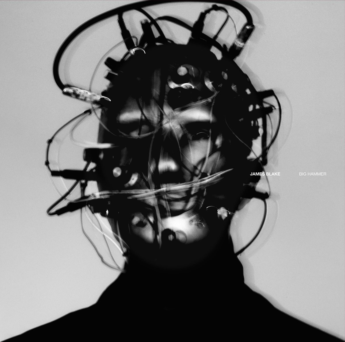 Black and white image of a single artwork from Playing Robots Into Heaven by James Blake, showing the musician wearing headwear covered in cables which appear to be inserted into his head