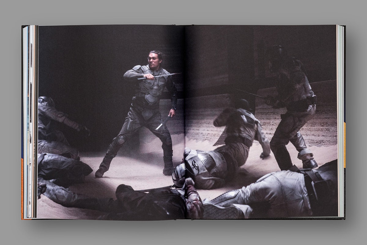 Image of a spread from a book about Dune, featuring a double page photograph of a person fighting a crowd surrounding them