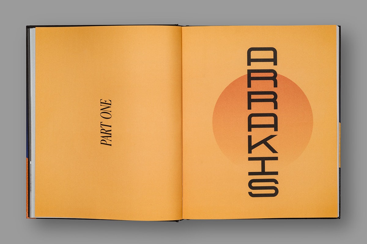 Image of a spread from a book about Dune, featuring an orange background across both pages, and the headline 'part one' rotated on its side on the left hand page and the headline 'Arrakis' arranged vertically on the right hand page