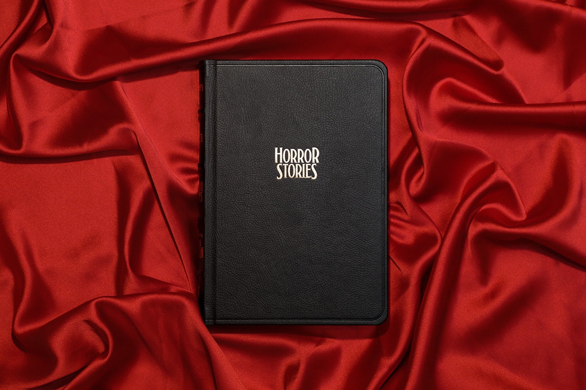 Photograph of McSweeney's Issue 71 Horror which comes in a black cover with white text that reads 'horror stories', shown resting on a pile of red silk fabric