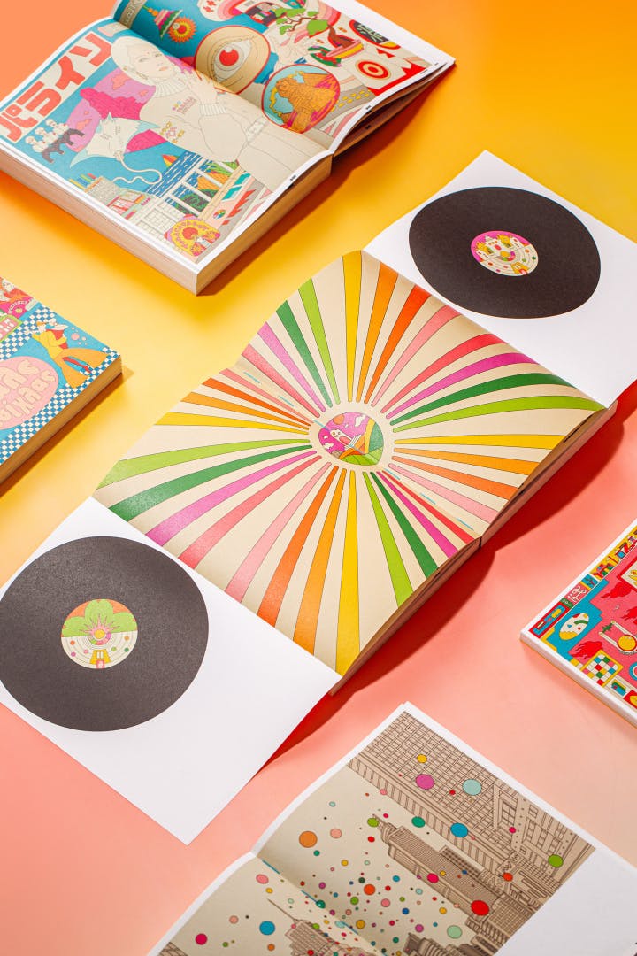 Photograph of multiple copies of Ardneks' book Coastalvision including one opened onto a page with a colourful sunburst illustration next to drawings of vinyl records