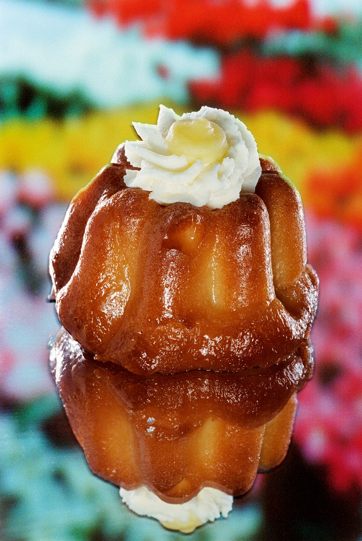 Image from Dream About Nothing by Bobby Doherty showing a small cannele cake topped with icing on top of a reflective surface