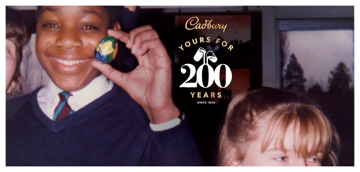 Ad from Cadbury 200th anniversary campaign showing a young person appearing to wear school uniform holding a Cadbury chocolate egg and smiling next to other children