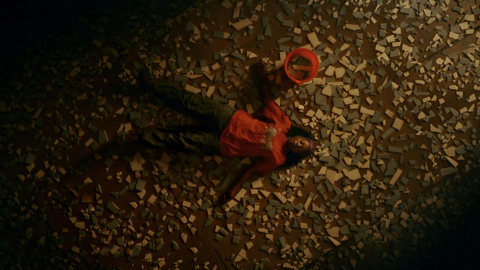 Still from B&Q You Can Do It ad showing an aerial view of a person lying on their back surrounded by a bucket and broken tiles