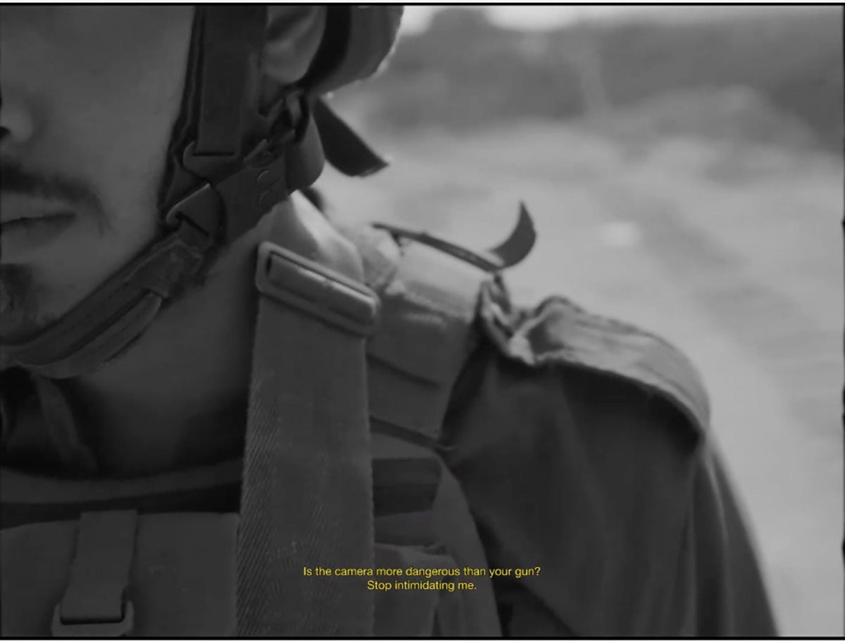 Black and white image showing a person wearing military clothing and helmet, with a caption at the bottom that reads 'Is the camera more dangerous than your gun? Stop intimidating me'