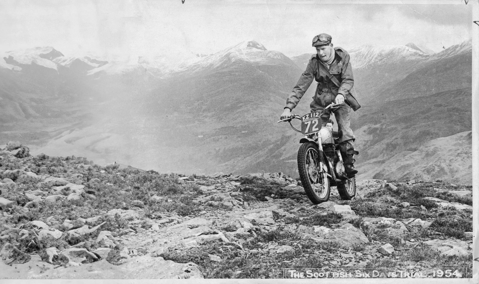 Black and white photo of motorcyclist Sammy Miller riding over a dirt track in the Belstaff centenary book