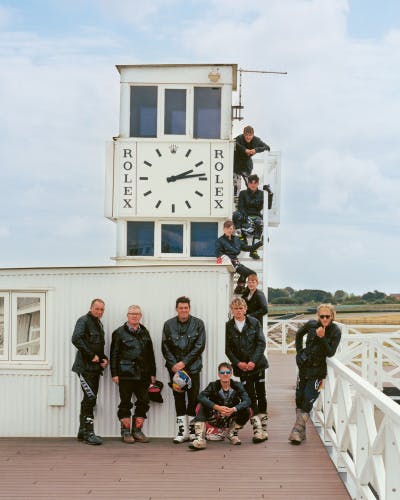 Photo from Belstaff centenary book of a group of men wearing leathers standing around a clock tower