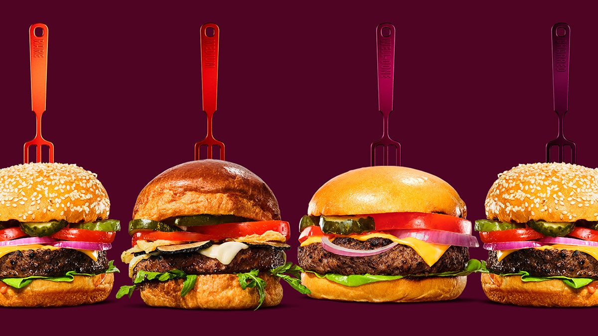 Image shows a line up of four Impossible burgers with different hued forks stuck in the bun