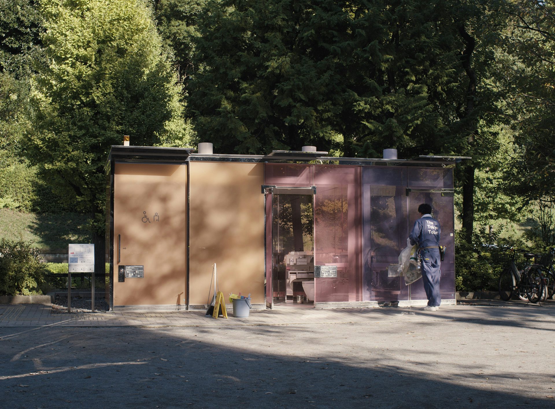 Film still from Perfect Days showing the pastel coloured glass public restroom in a Tokyo park