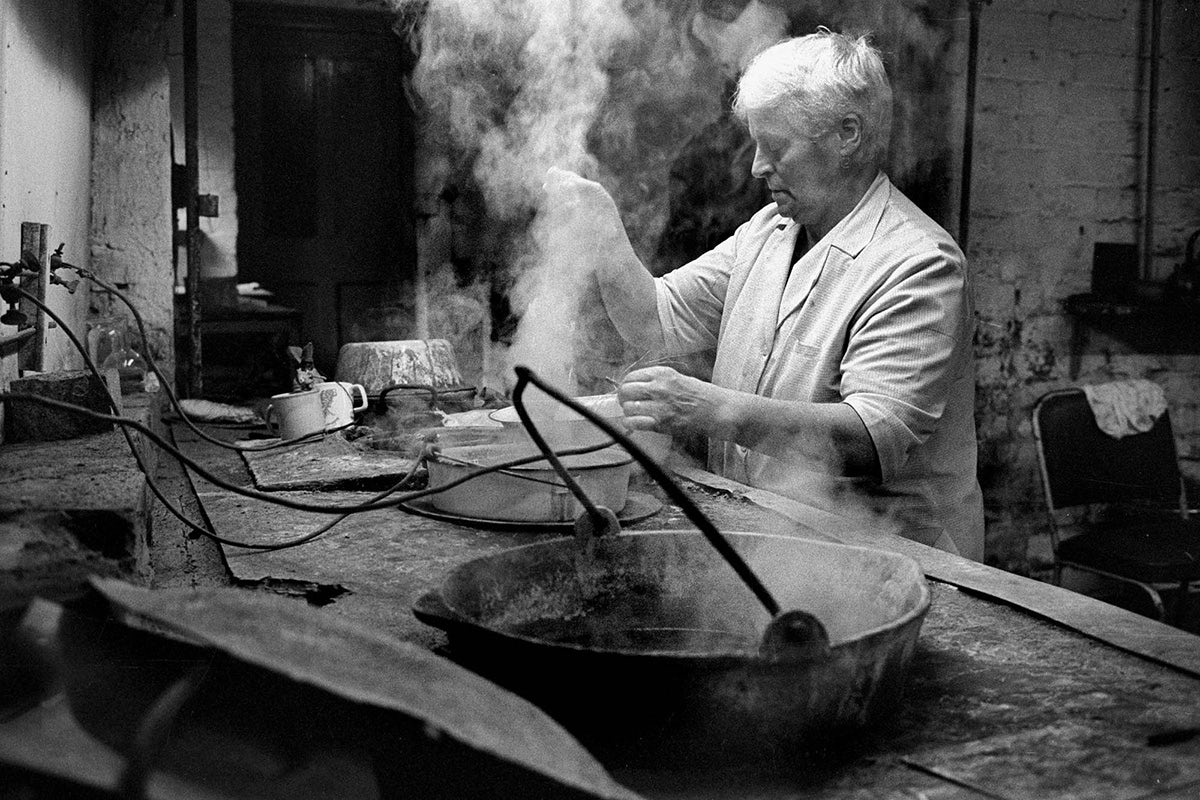 Black and white photograph from Vulcan's Forge showing a person at work standing over steaming buckets