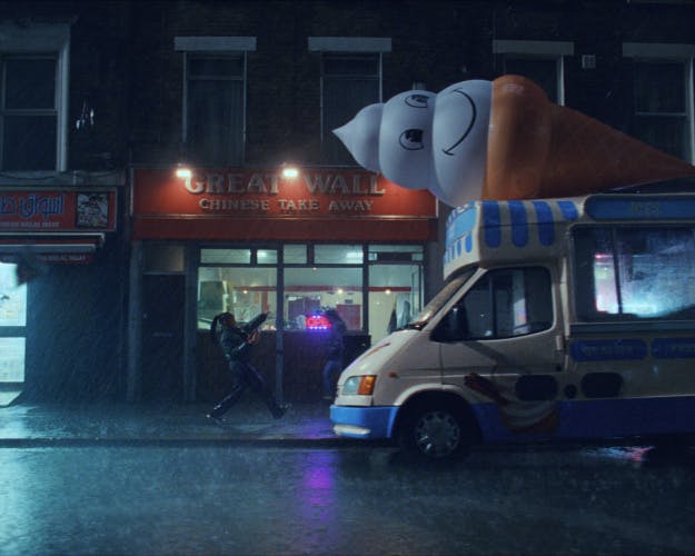 Young person dancing on a rainy night outside a takeaway restaurant next to an ice cream truck