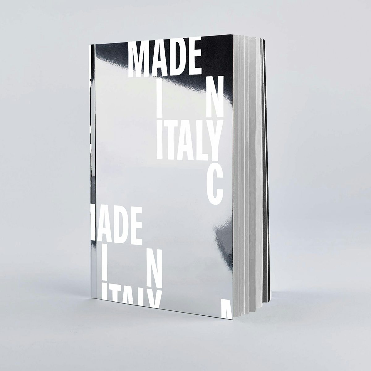 Shiny silver book cover that reads 'Made in Italy' and 'NYC' arranged so the common letters intersect