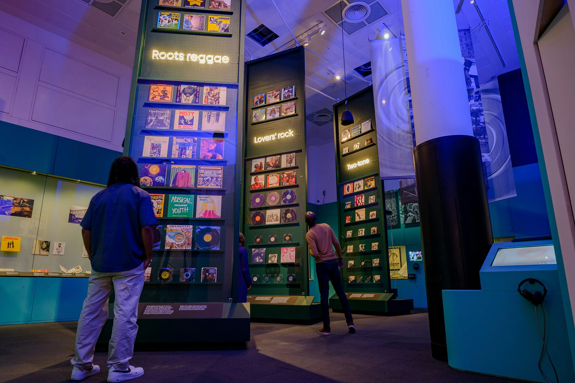 People standing in front of ceiling height installations covered in record sleeves