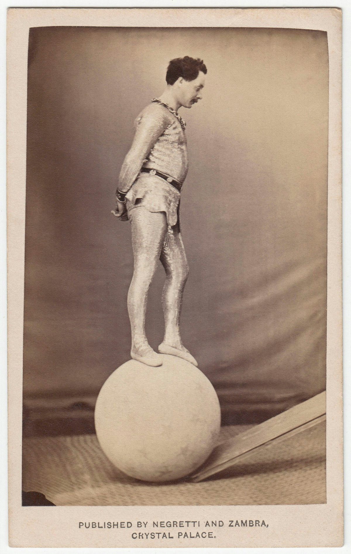 Sepia toned photo of a gymnast balanced on a large ball