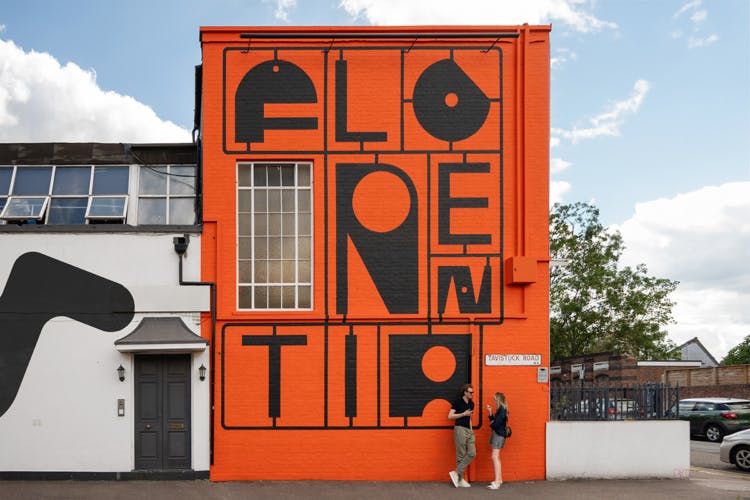 The word 'Florentia' painted onto the side of an orange building, featuring quirky unevenly shaped lettering