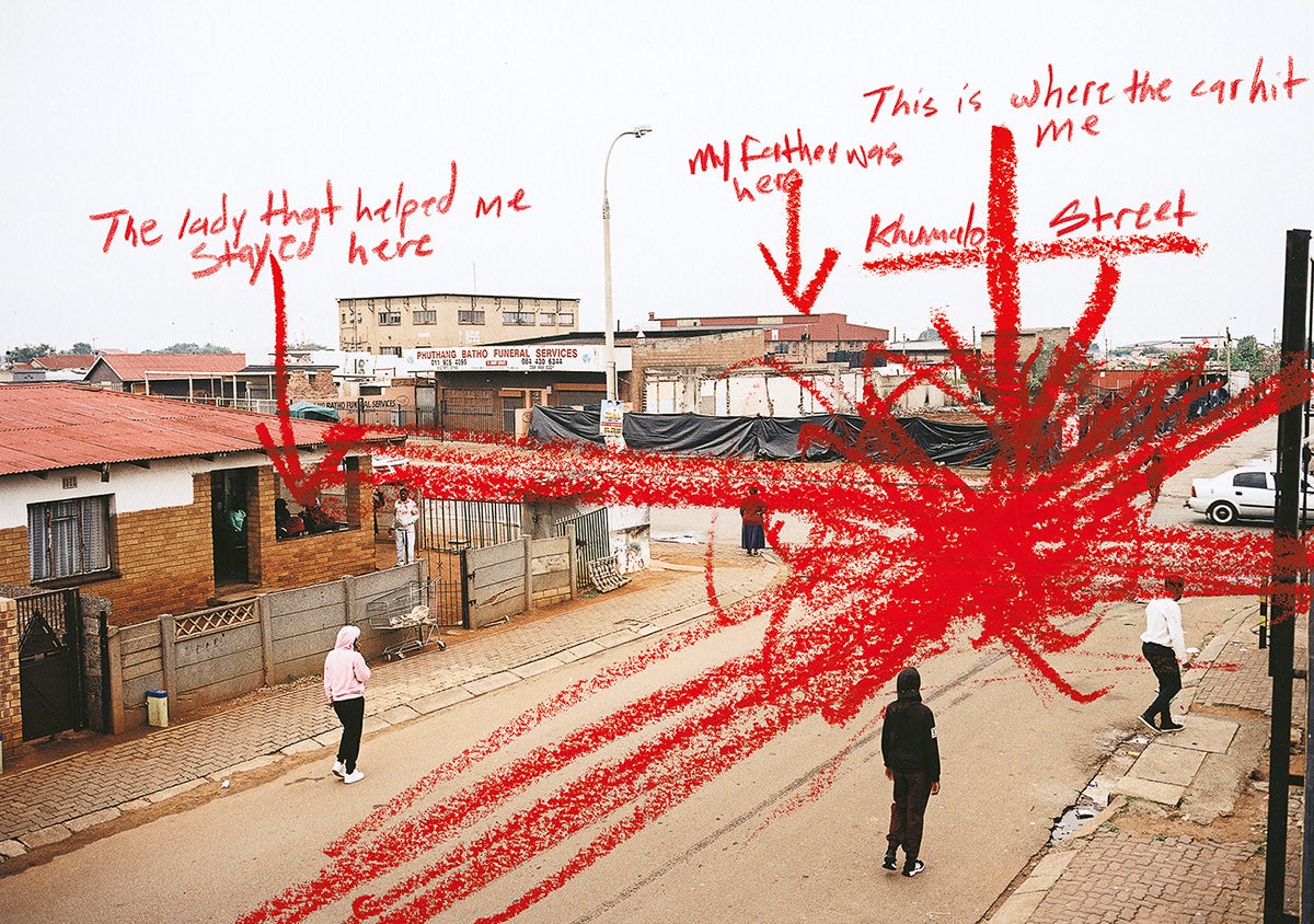 A crossroads in a South African township where several people walking in the street. The photo has been annotated in red crayon with arrows indicating specific points on the map
