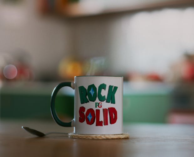 A mug on a kitchen table featuring the words Rock Solid in angular red and green letters