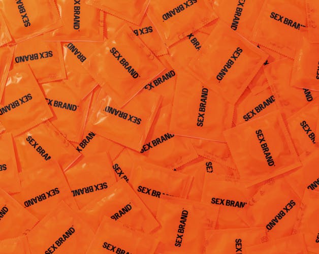 Aerial view of a pile of orange condom packets labelled Sex Brand