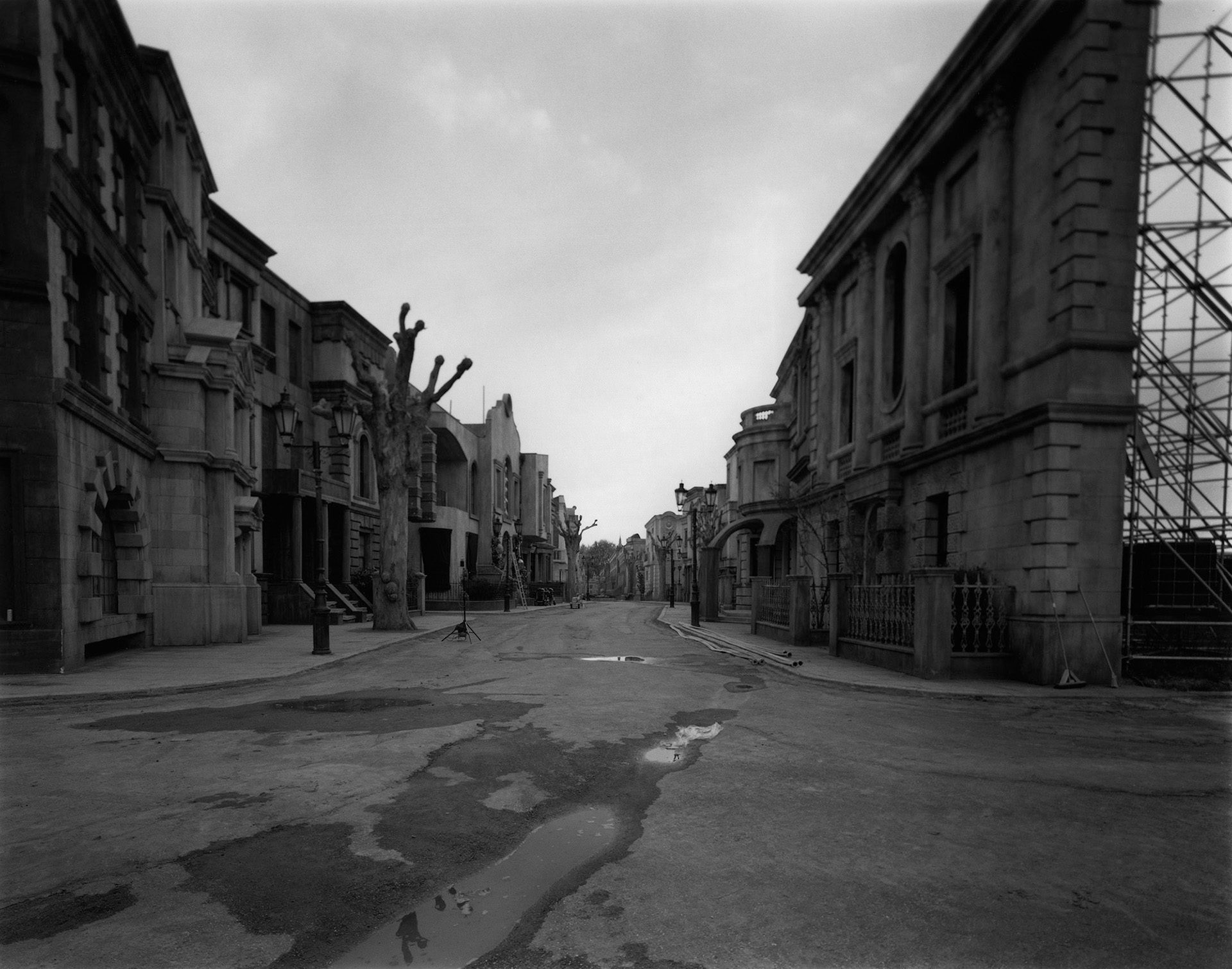 Black and white photo of a set of Poor Things designed in the style of Victorian era street in London. The scaffolding holding up the set is visible in the frame