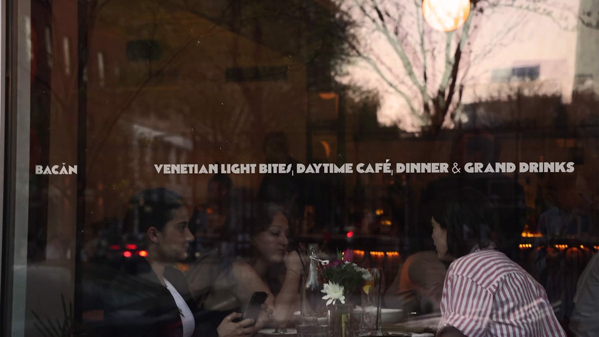A restaurant window displaying the line 'Venetian light bites, daytime cafe, dinner and grand drinks'