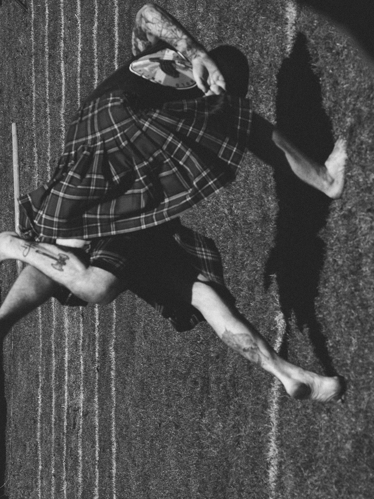 Black and white photo by Robbie Lawrence showing two people wearing kilts wrapped in a contorted position on a playing field