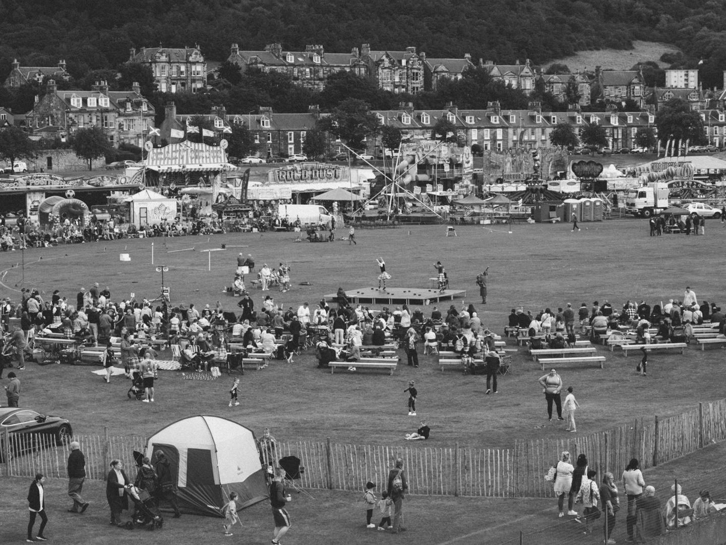 Black and white photo by Robbie Lawrence showing a Highland Games event in a field with tents and benches