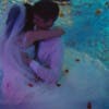 Still from the music video for Treat Each Other Right by Jamie xx, showing a bride and groom embracing in a swimming pool