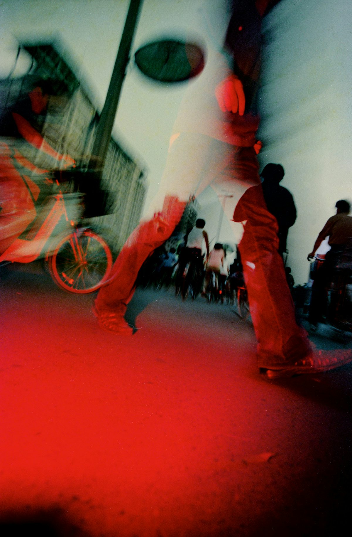 Red hued photograph by Mo Yi of a street scene taken near ground level