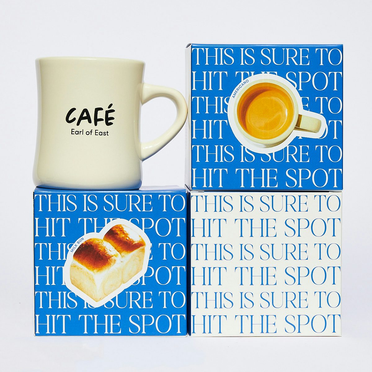 Three blue and white square boxes with a beige mug labelled 'cafe' resting on one box