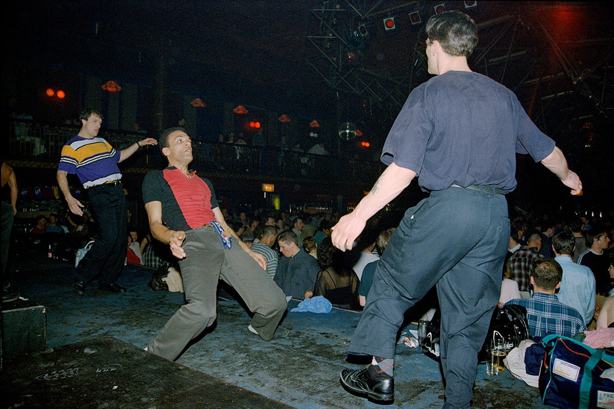 People dancing exuberantly on a stage in a busy club