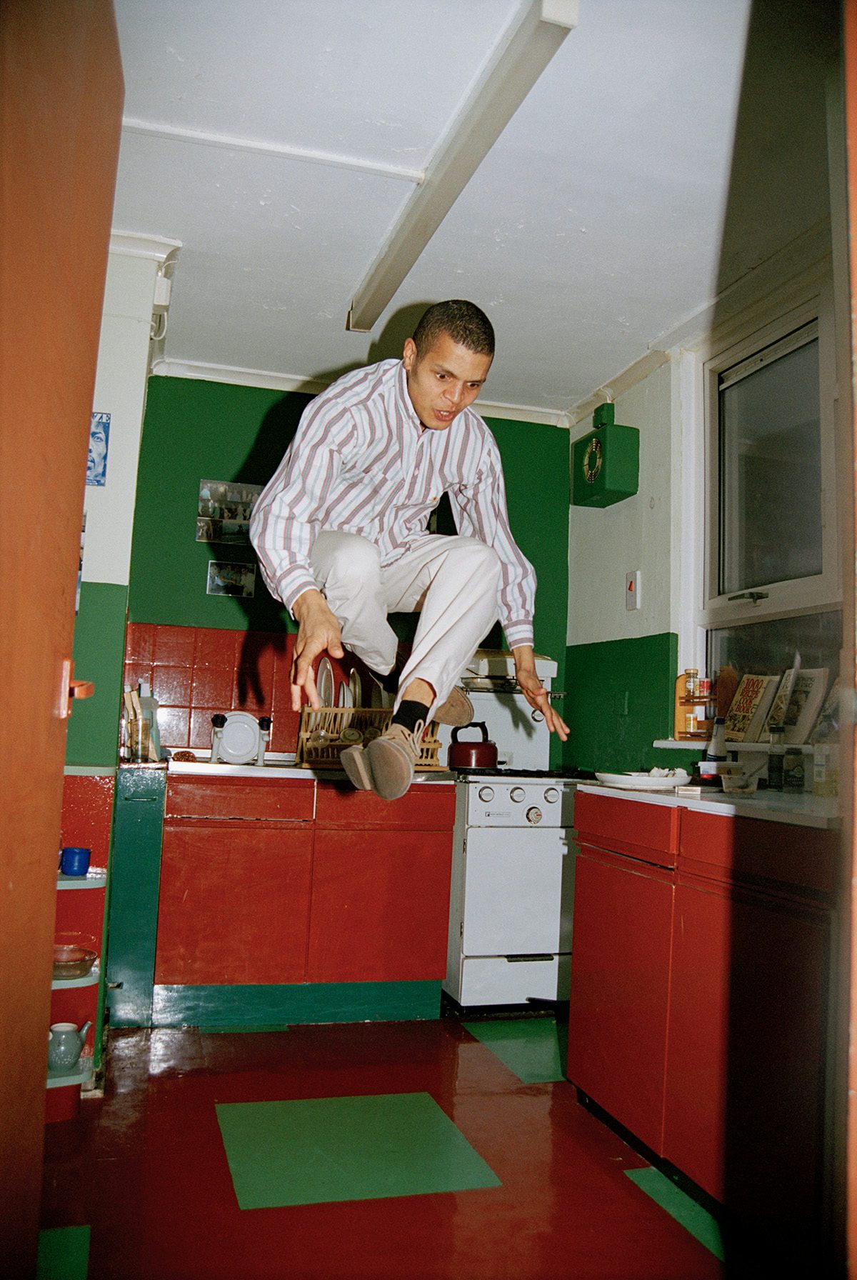 A person jumping up in a bright red and green kitchen