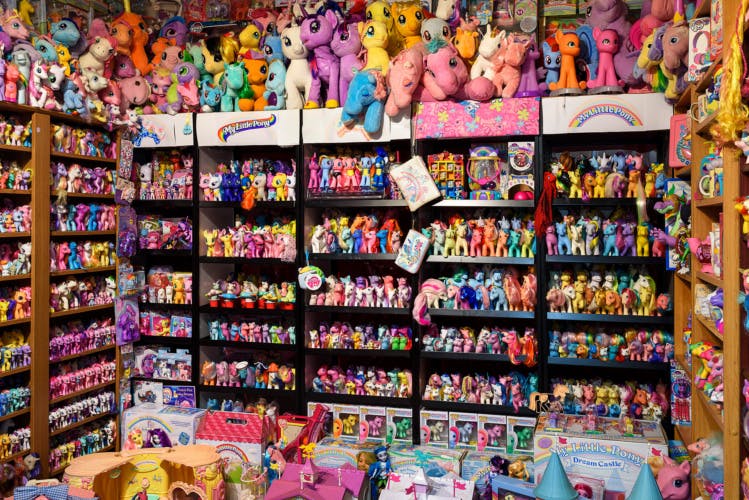 Exhibition installation of bookshelves entirely filled with colourful toys and figurines