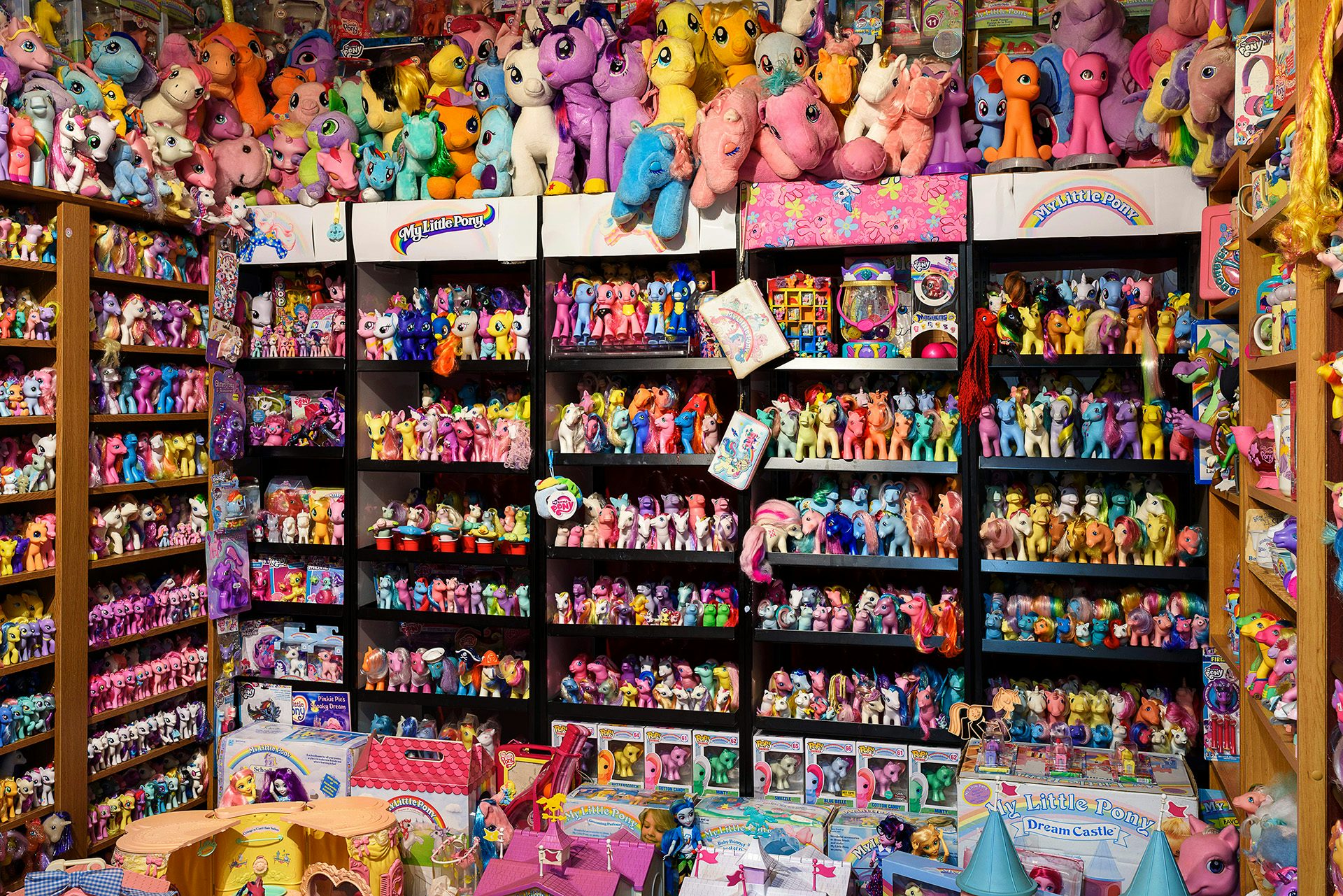 Exhibition installation of bookshelves entirely filled with colourful toys and figurines
