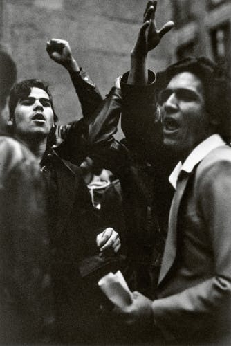 Black and white photo by Louis Stettner of a group of striking workers with their arms raised in the air