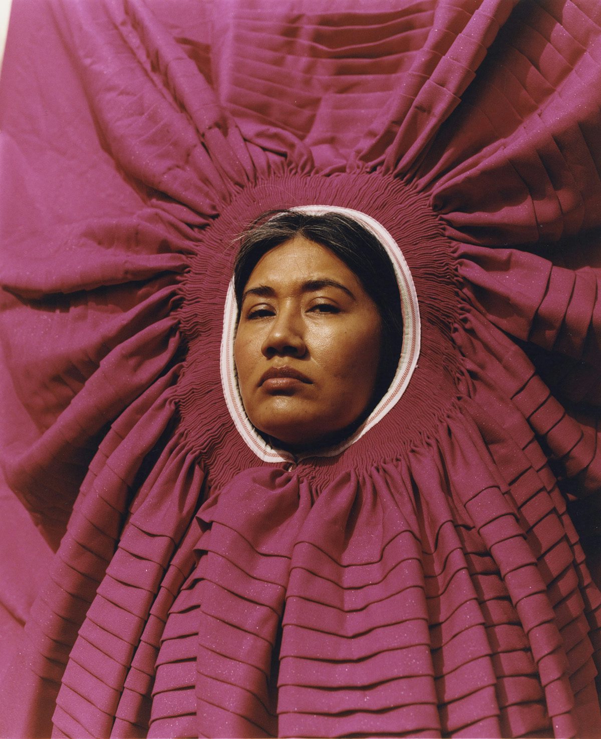 Photo by Ana Margarita Flores of a person wearing a purple circular garment on their head which frames their face