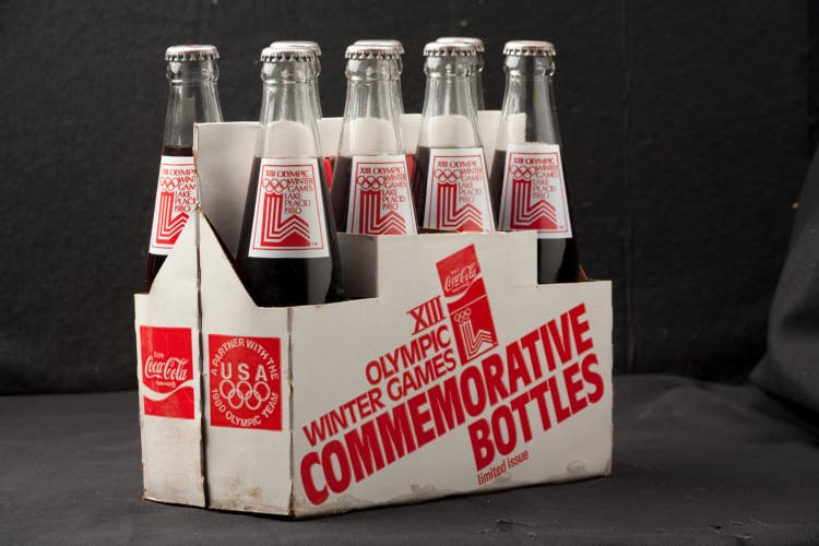 Eight pack of Coca-Cola glass bottles in a white and red commemorative cardboard holder for the 1980 Winter Olympic Games