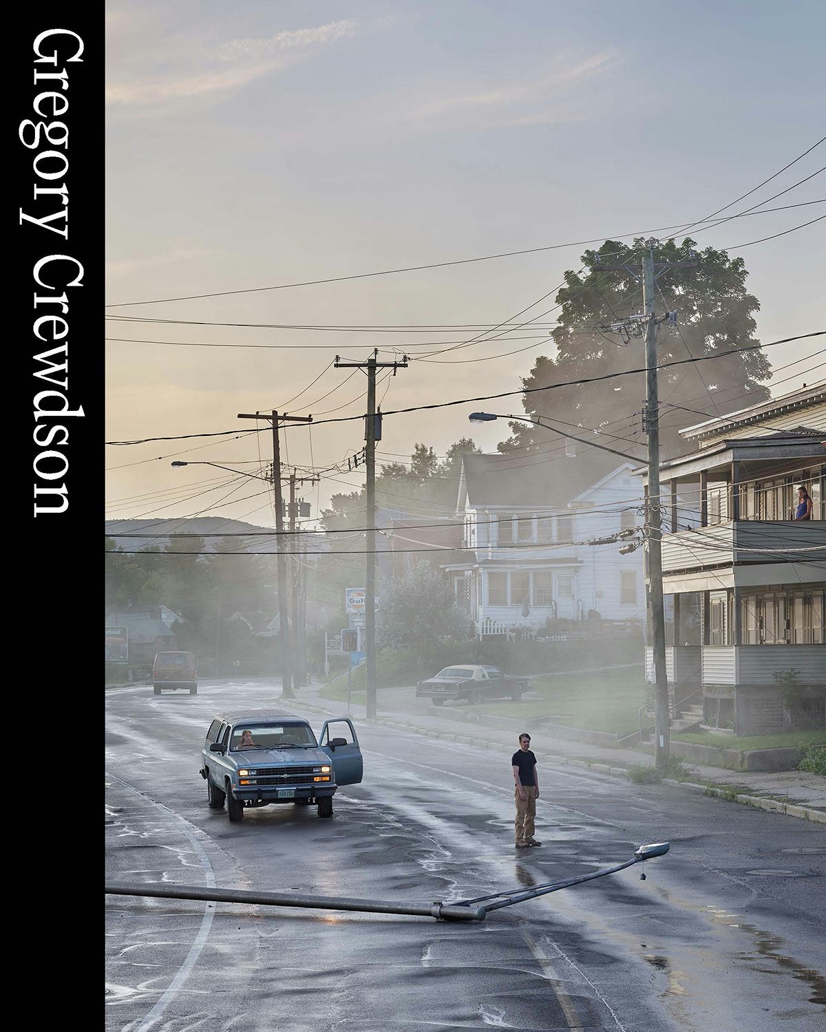 Book cover of Gregory Crewdson's monograph, featuring a desolate street scene of a car with its doors open and a person standing next to it
