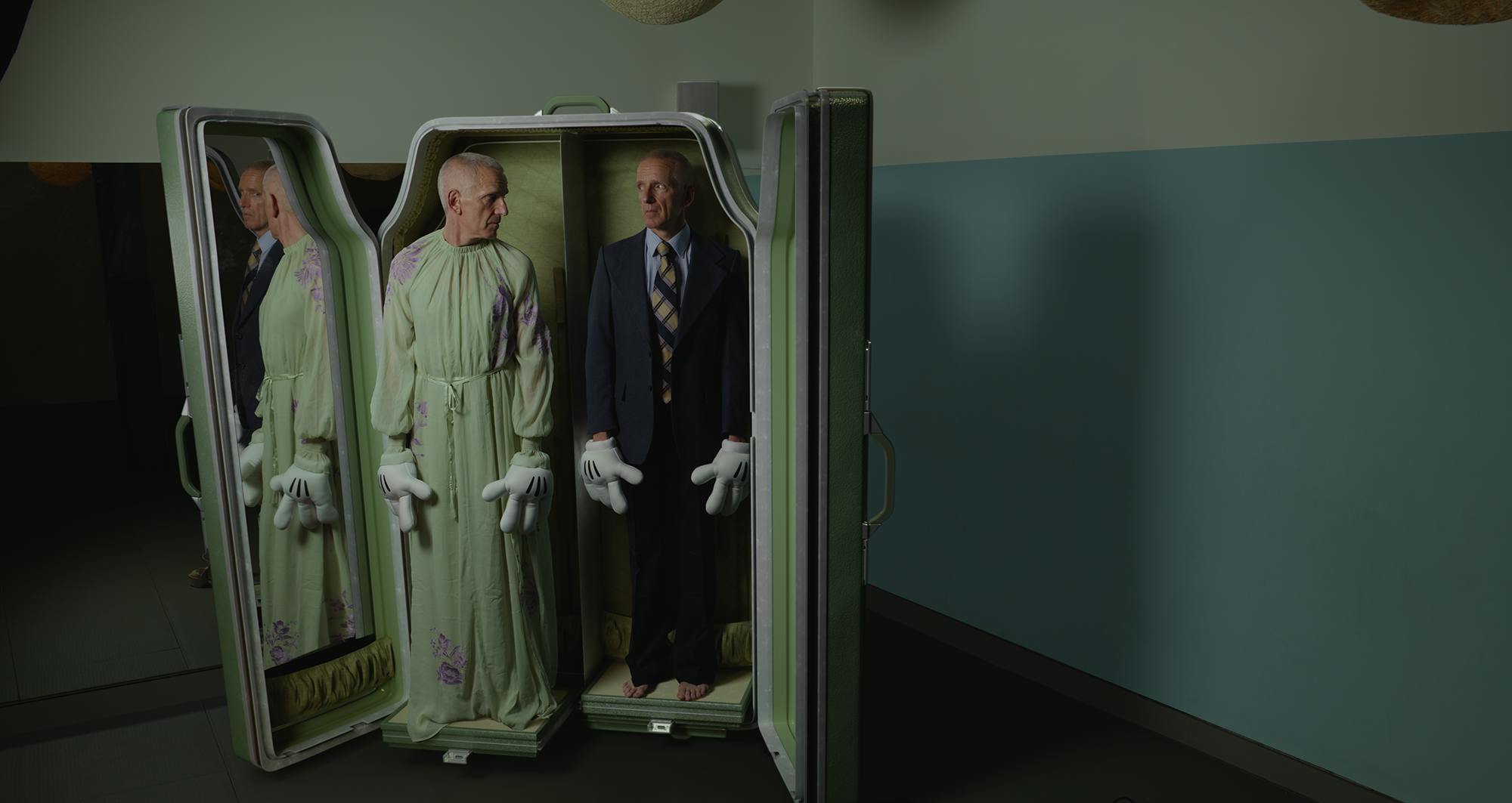 Two identical men stand inside a wardrobe