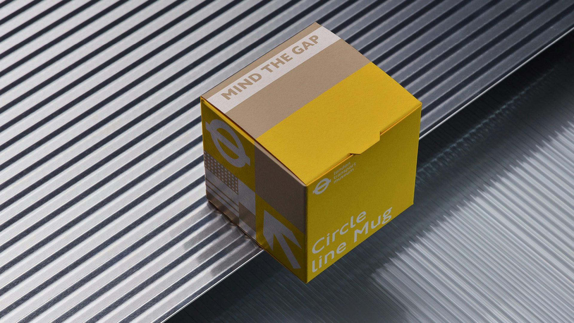 A cube shaped London Transport Museum packaging box in a brown and yellow palette