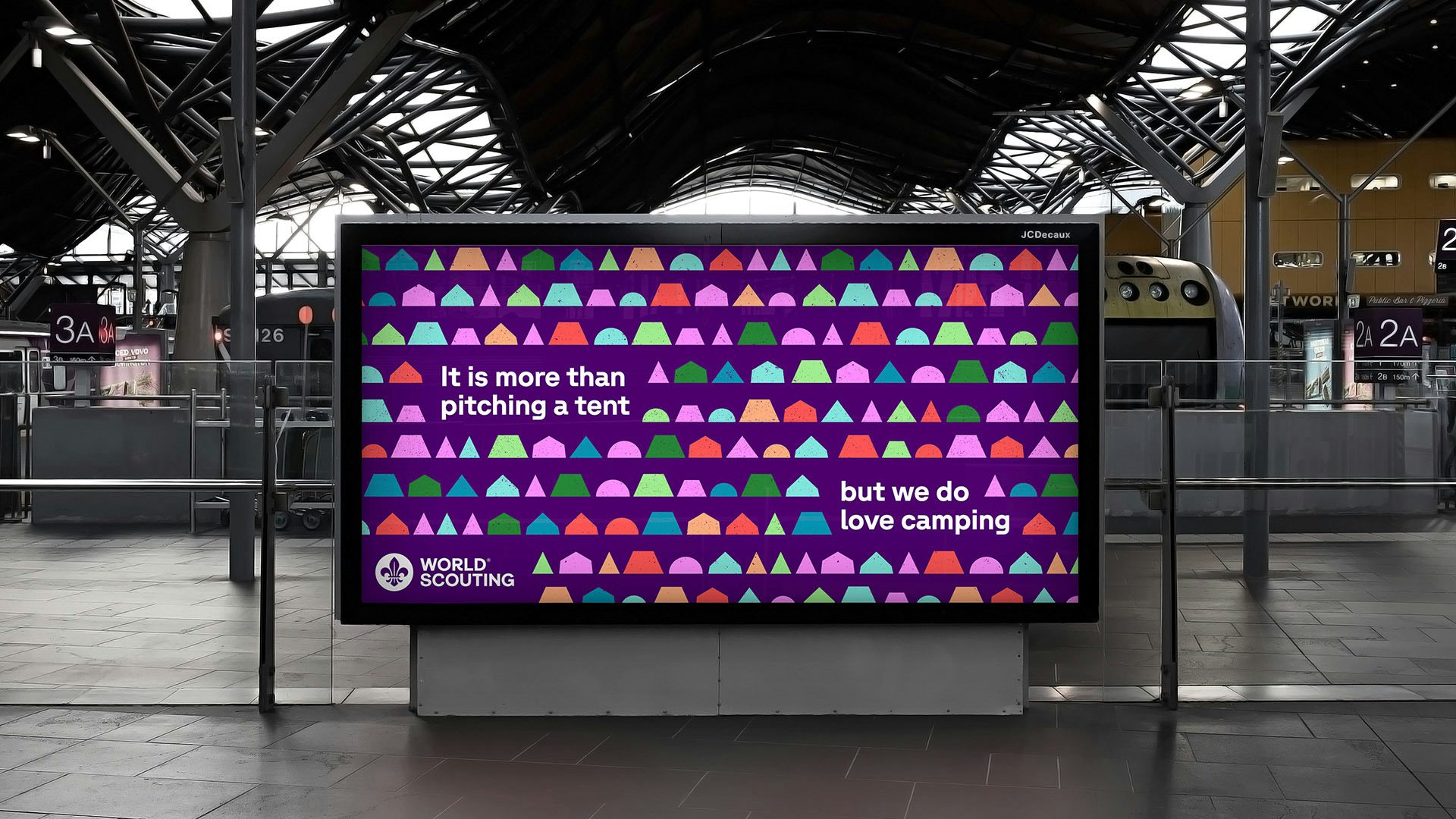 A digital display for World Scouting featuring the line 'it is more than pitching a tent, but we do love camping' against a colourful background of geometric shapes