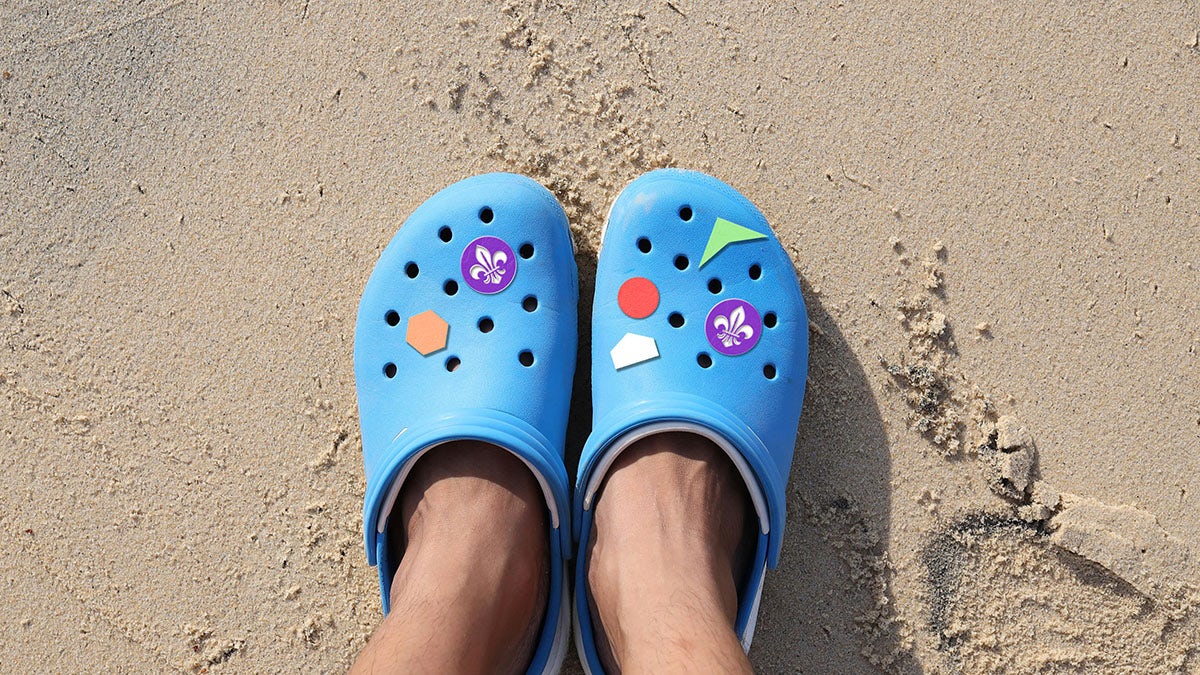 Blue Crocs with World Scouting badges including the purple fleur de lis emblem