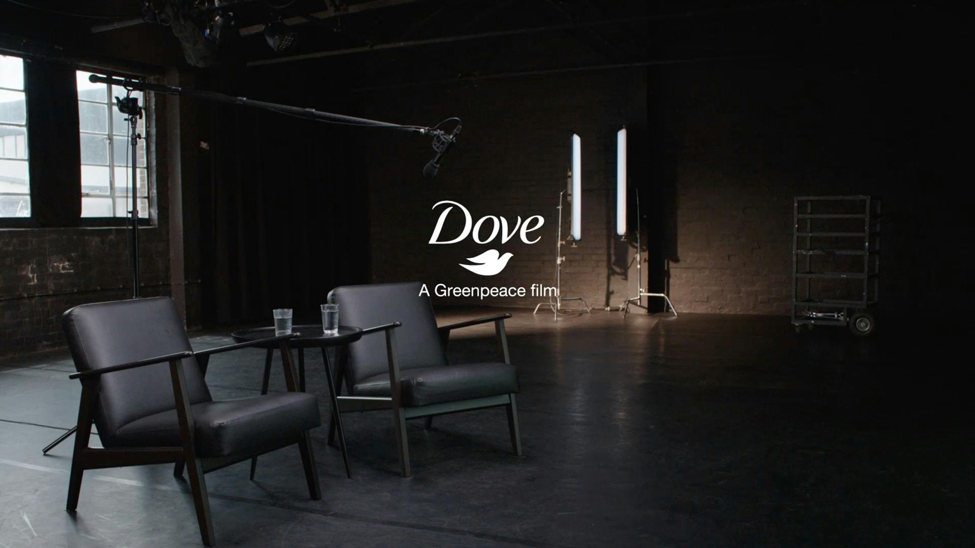 A darkened studio with two armchairs, and a Dove logo and the line 'A Greenpeace film' laid over the image