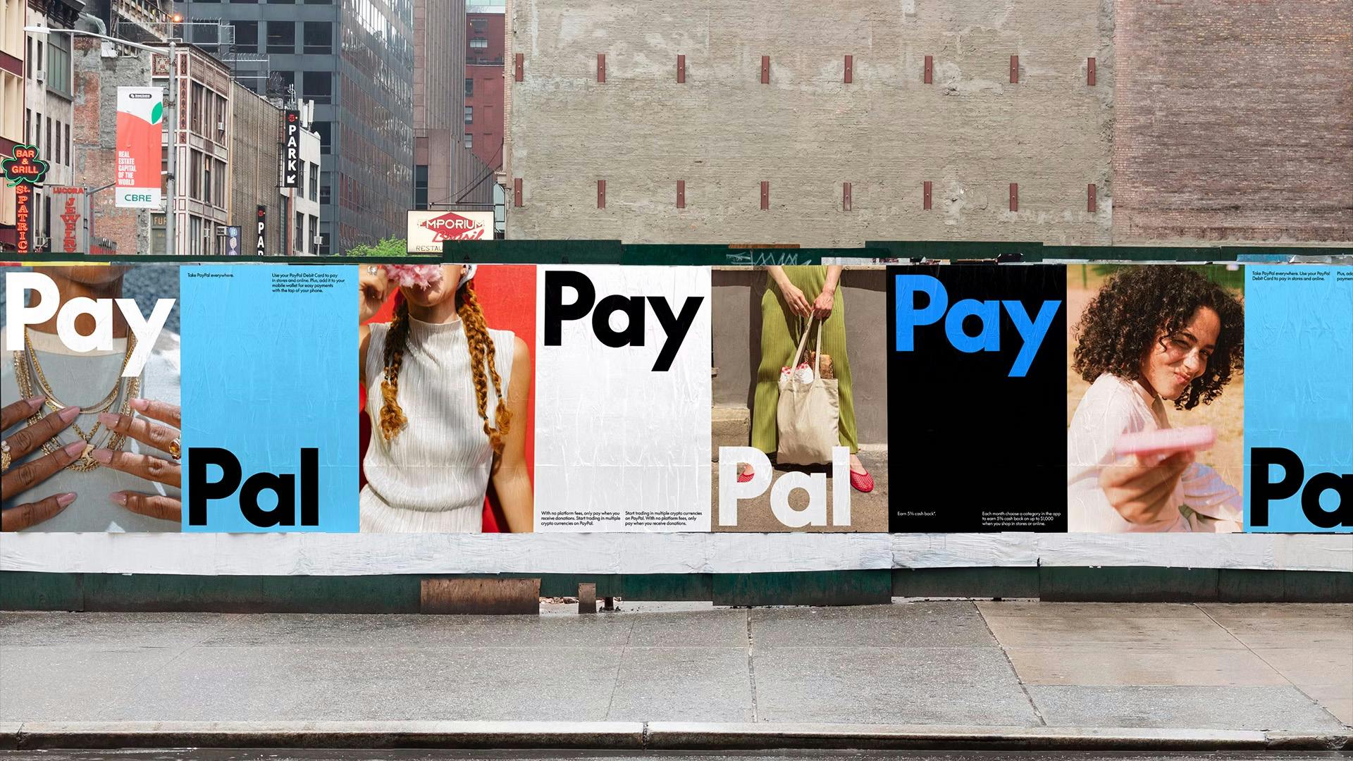 A wall covered in flyposters that read 'pay' and 'pal' and display PayPal's new branding system by Pentagram